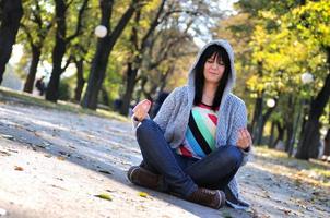 Brunette nette junge Frau, die in der Natur sitzt foto