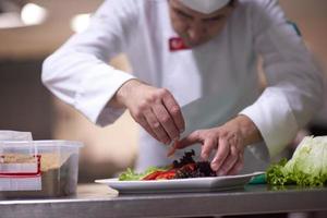 Küchenchef in der Hotelküche bereitet Speisen zu und dekoriert sie foto