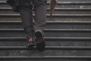 Geschäftsmann, der mit Regenschirm in der Hand die Treppe hinaufsteigt foto