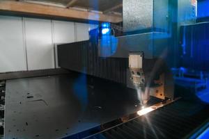 Funken fliegen aus Maschinenkopf für die Metallbearbeitung Lasermetall auf metallurgischem Anlagenhintergrund. herstellung fertiger teile für das konzept der automobilproduktion foto