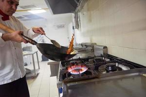 koch in der hotelküche bereitet essen mit feuer zu foto