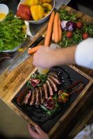 Blick von oben auf den Koch, der Steak-Fleischplatte fertigstellt foto