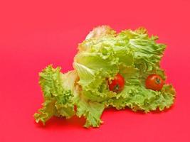 frischer Salat und Tomaten auf rotem Hintergrund foto