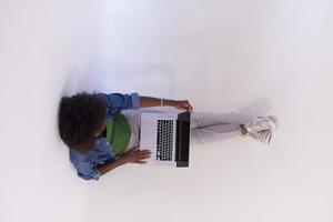 afroamerikanerfrau, die auf dem boden sitzt, mit laptop-draufsicht foto