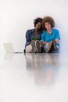 Multiethnisches Paar sitzt mit Laptop und Tablet auf dem Boden foto