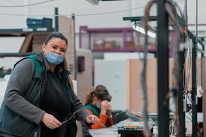 Eine fettleibige Frau arbeitet in einer Schwermetallfabrik und trägt wegen einer Coronavirus-Pandemie eine Maske im Gesicht foto