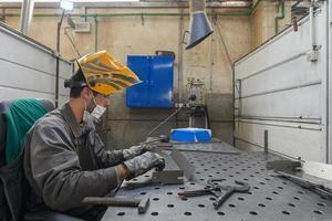 arbeiter der metallindustrie, die in der fabrik arbeiten und während der coronavirus- oder covid19-pandemie eine schützende gesichtsmaske tragen. foto