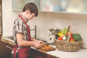 Junge bereitet Gemüse in der Küche zu - vegetarisch gesunde Menschen