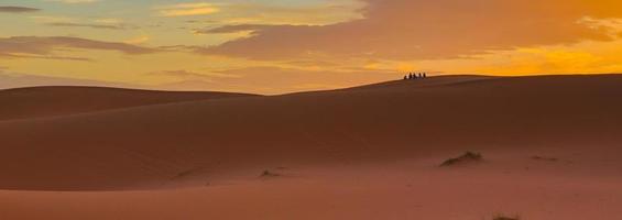 Sahara Wüste Marokko. Menschen in der Ferne beobachten den Sonnenaufgang. foto