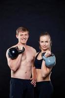 attraktive Fitnessleute, die Kettlebells lokalisiert über grauem Hintergrund halten