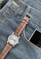 Armbanduhr und Smartphone auf Jeans foto