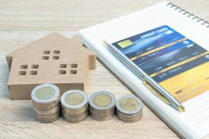 Hausmodell und Münzen mit Kreditkarte auf Holztisch foto