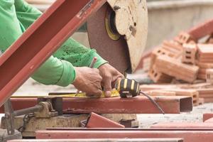 arbeiter, der metall mit schleifmaschine auf der baustelle schneidet foto