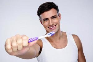 Porträt eines lächelnden Mannes, der Zahnbürste hält