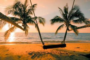 holzschaukel schöner sonnenuntergang am meeresstrand mit palme und blauem himmel für reisen im urlaub entspannen sie sich, fotostil vintage foto