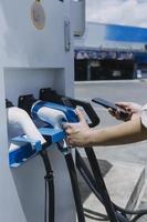 hand, die ein ladegerät in eine elektroautosteckdose einsteckt. elektroauto oder ev wird an der station aufgeladen foto