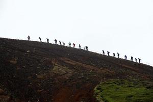 gruppe von wanderern, die einen vulkan in island hinaufgehen foto