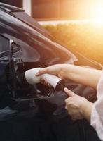 hand, die ein ladegerät in eine elektroautosteckdose einsteckt. elektroauto oder ev wird an der station aufgeladen foto