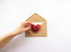 eine frau, die ein rotes herz in der hand hält und einen umschlag zum valentinstag einsendet foto