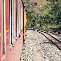 Spielzeugeisenbahn, die sich auf Berghängen bewegt, schöne Aussicht, ein Seitenberg, ein Seitental, das sich auf der Eisenbahn zum Hügel bewegt, inmitten grüner Naturwälder. spielzeugeisenbahn von kalka nach shimla in indien, indischer zug foto