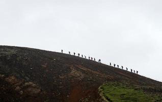 gruppe von wanderern, die einen vulkan in island hinaufgehen foto