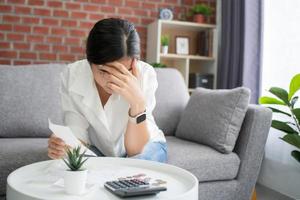asiatische Frauen sind gestresst und verwirrt über die Berechnung von Ausgaben aus Rechnungen oder Rechnungen, haben kein Geld zu zahlen, Hypotheken oder Darlehen. schulden-, bankrott- oder bankrottkonzept. foto