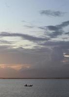 Fischersilhouette auf seinem Boot foto