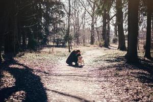 Mädchen in einem Mantel, der einen Hund umarmt foto