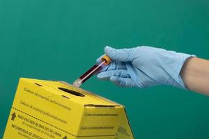 Sammelbox für kontaminierte Krankenhausabfälle mit der Hand, die einen Vakuumbehälter platziert foto