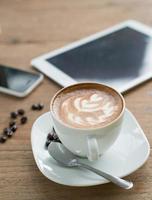Tasse Kaffee auf dem Tisch im Café mit Tablette foto