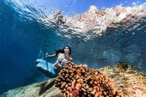 schöne meerjungfrau, die unter wasser im tiefblauen meer schwimmt foto