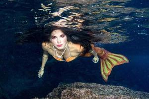 Meerjungfrau, die unter Wasser im tiefblauen Meer schwimmt foto