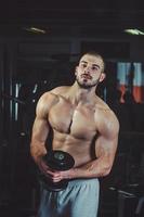 schöner muskulöser Mann, der im Fitnessstudio trainiert