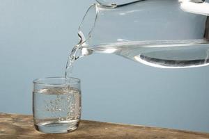 Person, die eine Tasse Wasser mit einem Glas füllt. foto