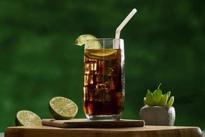 Cuba Libre Drink mit Limette und Eis auf rustikalem Holztisch foto