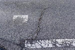 Detailansicht auf Asphaltoberflächen verschiedener Straßen und Straßen mit Rissen foto