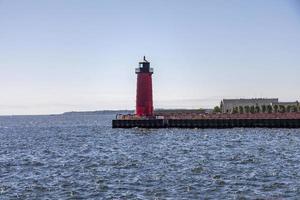 Roter und schwarzer Leuchtturm auf einem Steg an einem See foto