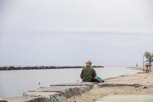 Mann sitzt auf den Felsen am Meer foto