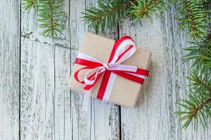 weihnachtsgeschenkboxen mit rot-weißem band auf holzhintergrund mit tannenzweigen. foto