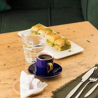 eine Tasse Kaffee in der Nähe von Glas Wasser und Baklava foto