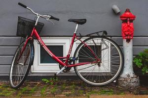 Rotes Fahrrad mit Eimer in der Nähe der Feuerlöschpumpe foto
