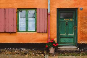 orange Wand, grüne Fenster und roter Blumentopf foto