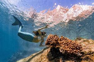 Meerjungfrau, die unter Wasser im tiefblauen Meer schwimmt foto