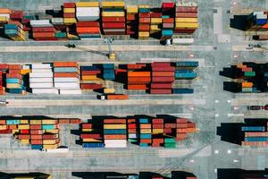 Luftdrohne von oben nach unten auf Container, die über ein geschäftiges Hafen-, Logistik- und internationales Handelskonzept verteilt sind foto