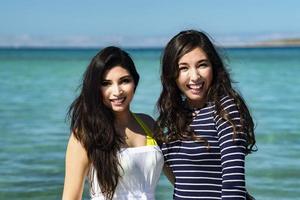 Zwei Mädchen lächeln verliebt am Strand foto