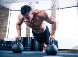 muskulöser Mann, der Liegestütze im Fitnessstudio tut foto