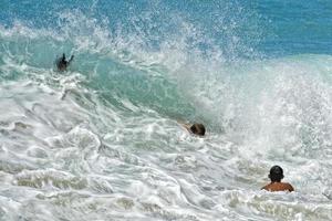 Kinder spielen in Meereswellen auf Hawaii foto