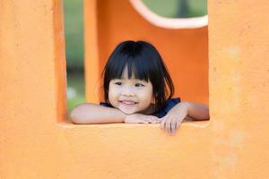 junges asiatisches Mädchen im Fenster genießt Spielplatz foto