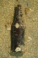 verkrustete Flasche auf dem Sandboden des Ozeans foto