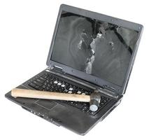 Alter beschädigter Laptop mit Hammer auf der Tastatur foto